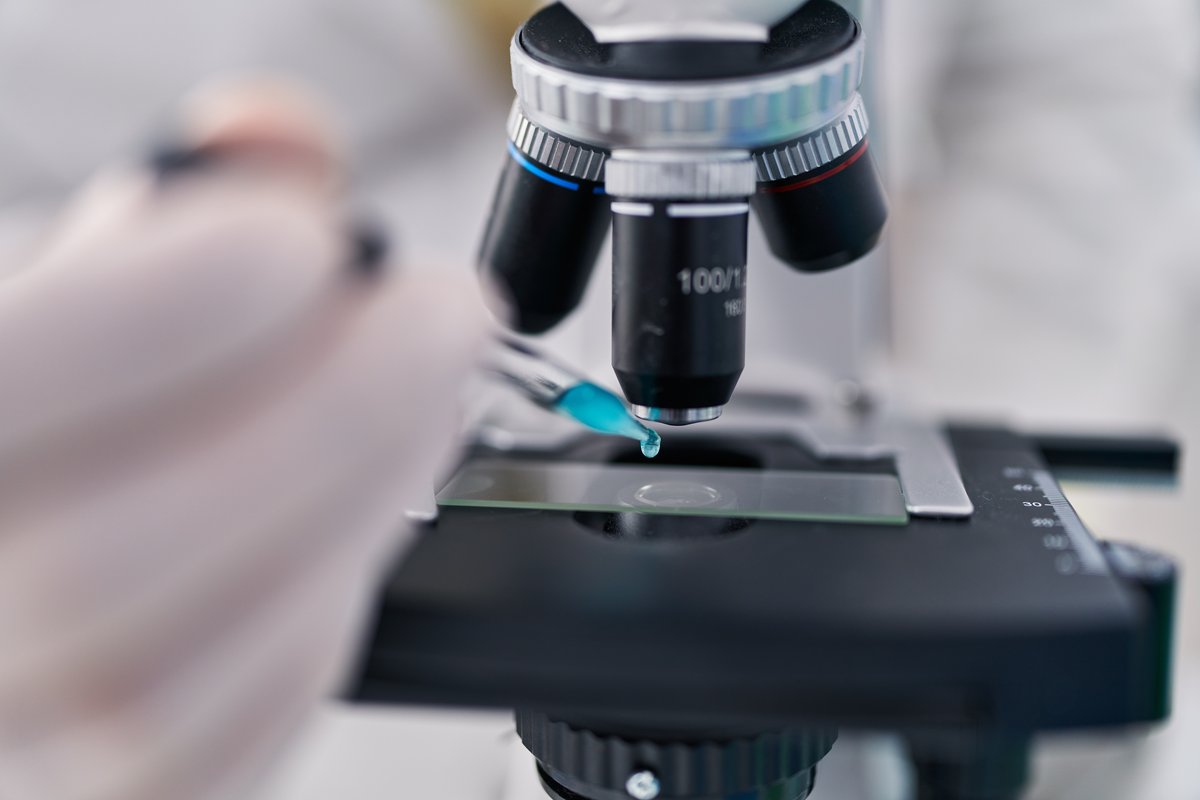 Persona investigadora examina una muestra al microscopio