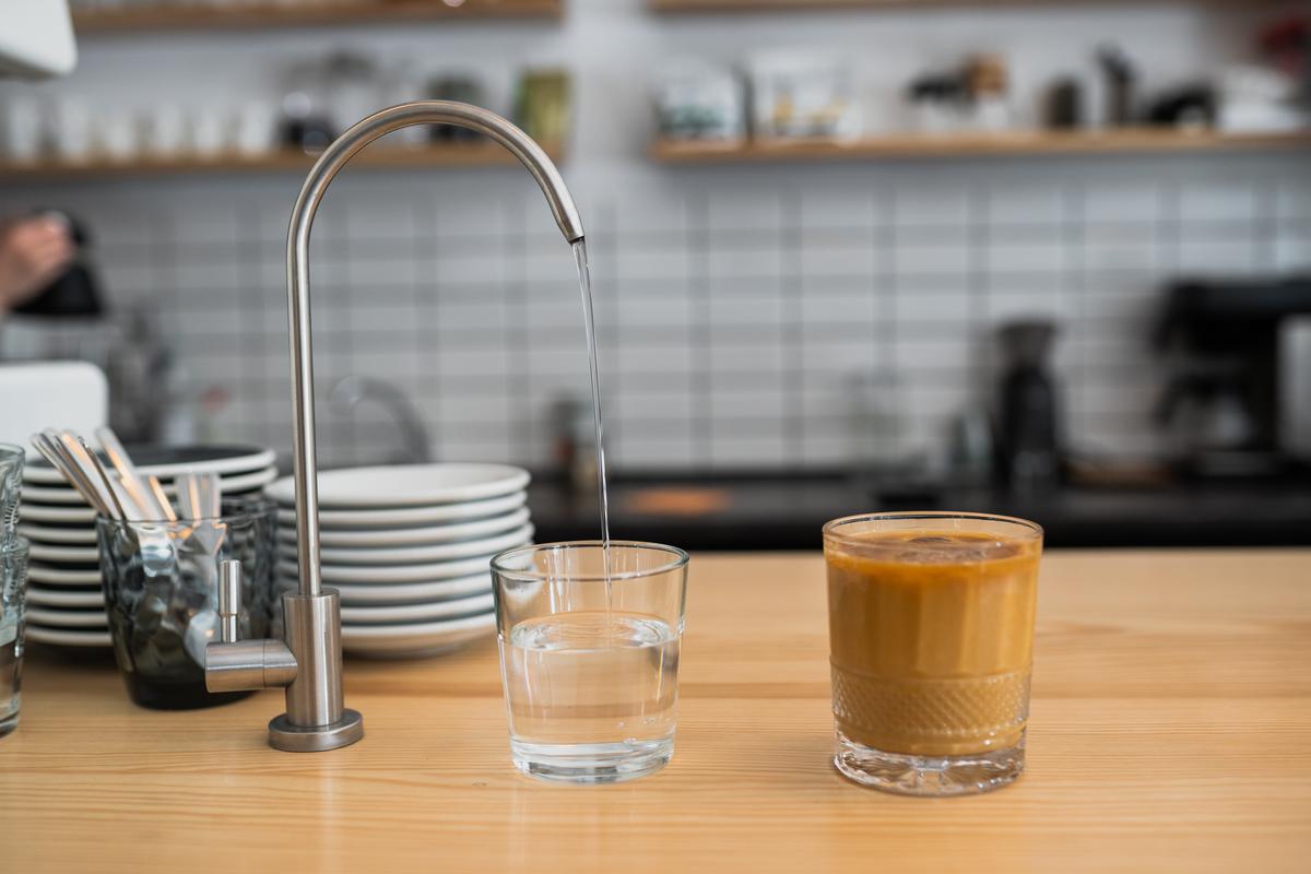 El agua potable cae del grifo a un vaso