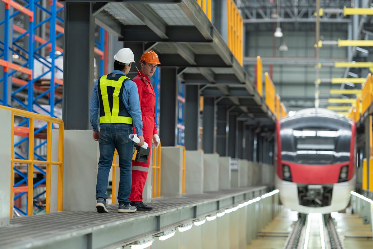 Two workers in work clothing at a depot in front of an electric multiple unit