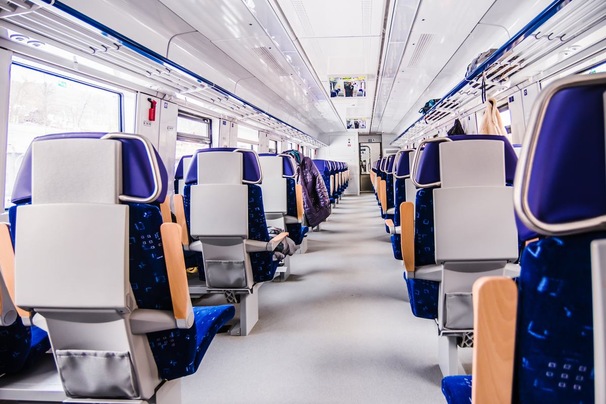 Empty passenger area of a modern train with rows of seats and a central aisle